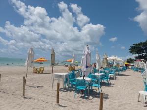 uma praia com mesas, cadeiras e guarda-sóis em Casa morada da praia 5 em Peroba