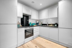 a kitchen with white cabinets and a wooden floor at 1 Bed Stunning City Apt, Southampton Ocean Village, Sleeps 4! By Blue Puffin Stays in Southampton