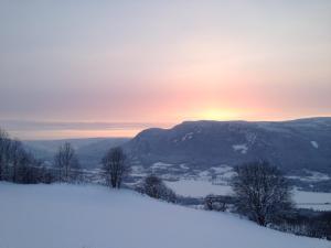 a snow covered hill with the sunset in the background at Hafjell Farmhouse in Øyer