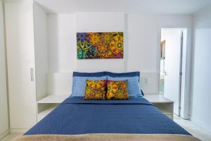 アハイアウ・ド・カボにあるCobertura Pé na Areia- Piscina, Churrasqueira, Vista Mar e a 50m da Praia dos Anjosのベッドルーム1室(壁に絵画が描かれた青いベッド1台付)