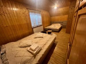 2 Betten in einem Zimmer mit Holzwänden in der Unterkunft Vila Rustik Straja in Lupeni