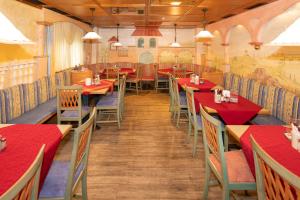 uma sala de jantar com mesas vermelhas e cadeiras num restaurante em Hotel Wirt Z'Minsta em Altmünster