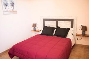 1 dormitorio con 1 cama roja grande y 2 almohadas en Casa rural El Cestero, en Castellote
