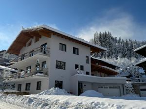 uma grande casa branca na neve em Appartement Dorfblick em Auffach