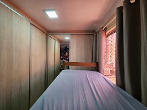 Dormitorio pequeño con cama y ventana en Conforto Urbano, Apartamento Acolhedor en Maringá
