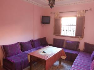 a living room with a purple couch and a table at IMLIL VALLEY Garden in Imlil