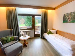 a bedroom with a bed and a chair and a window at Landgasthof Jostalstüble in Titisee-Neustadt