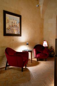 una sala de estar con 2 sillas rojas y una mesa. en Lo Stemma Luxury Boutique Hotel, en Matera