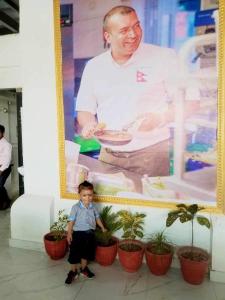 een kleine jongen die voor een foto van een chef staat bij Mithila Thali By Chef Santosh Shah in Janakpur