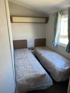 two beds in a small room with a window at Perranporth Holiday Park in Perranporth