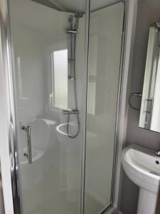 a white bathroom with a shower and a sink at Perranporth Holiday Park in Perranporth