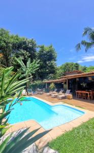 a swimming pool with a patio and a house at Vila Pitanga Trancoso in Trancoso