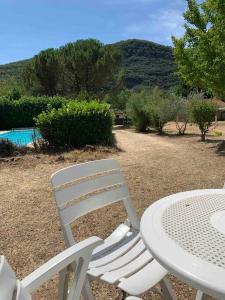 a white table and chairs with a table and a pool at Gîte 45 m2 3/4 personnes in Bessèges +1 photo