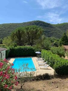 a swimming pool with lounge chairs and an umbrella at Gîte 45 m2 3/4 personnes in Bessèges