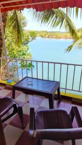 a table and chairs on a balcony with a view of the water at Entire River Villa in Canacona