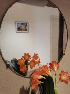 einen Spiegel mit einer Vase mit orangefarbenen Blumen darin in der Unterkunft Domus Lineker in Venafro