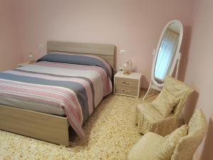 a bedroom with a bed and a chair and a mirror at Domus Lineker in Venafro