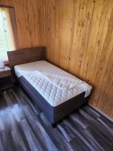 a bed in a room with a wooden wall at Cabaña Alto Naupe in Puerto Saavedra