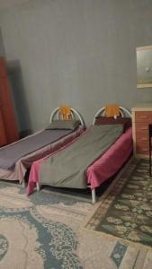 dos camas sentadas una al lado de la otra en una habitación en Hostel Praga, en Türkistan