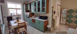 een keuken met groene kasten, een tafel en een koelkast bij Casa Anna B&B in Castellammare di Stabia