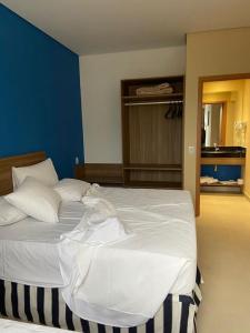 a bedroom with a large white bed with a blue wall at Apartamento completo no resort Water Park in São Pedro