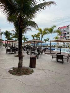 a patio with tables and chairs and a palm tree at Apartamento completo no resort Water Park in São Pedro