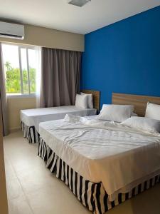 two beds in a bedroom with a blue wall at Apartamento completo no resort Water Park in São Pedro
