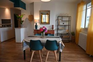 Grand appartement cosy-Hyper Centre-Place Verdun في تارْب: طاولة طعام مع كراسي و إناء من الزهور