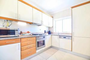 Una cocina con electrodomésticos blancos y gabinetes de madera. en Apartamento L14 by MTPhomes, en Albufeira