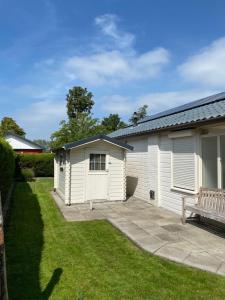 un hangar blanc avec banc à côté d'une cour dans l'établissement Bungalow Scheldezicht in Zeeland dicht bij zee, à Scherpenisse