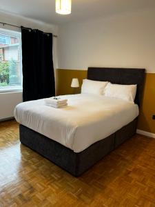 um quarto com uma cama grande e lençóis brancos em Dartford Stay em Kent