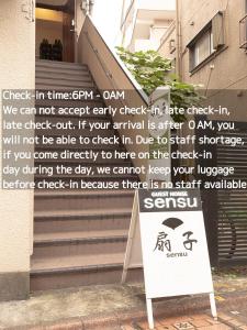 a sign sitting in front of a building with stairs at Guesthouse Sensu in Tokyo