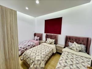 2 łóżka w pokoju z białymi ścianami w obiekcie شاليهات بست تايم محايل w mieście Muhayil