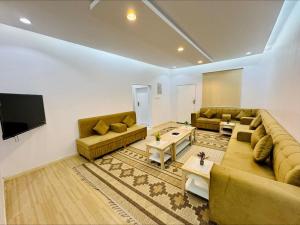 sala de estar con sofás y TV de pantalla plana. en شاليهات بست تايم محايل en Muhayil