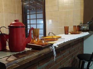 Hospedagem San Gonzales Two في سوروكابا: كاونتر عليه غلاية شاي حمراء وأطباق