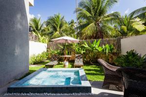 a swimming pool in a yard with chairs and an umbrella at Namorada Atauá in São Miguel dos Milagres
