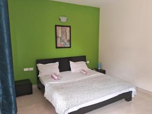ein Schlafzimmer mit einem Bett und einer grünen Wand in der Unterkunft Coconut Grove Holiday Apartment in Varca