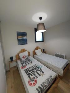een slaapkamer met 2 bedden en een hanglamp bij Appartement Mimizan Plage accès direct plage surveillée in Mimizan