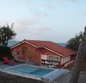 una casa rossa con una piscina di fronte di Les Lauriers du Rocher 1 a Le Diamant Altre 12 foto