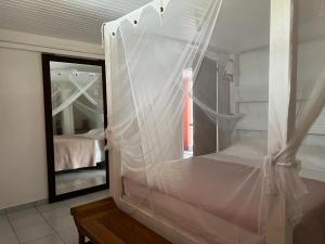 una camera con letto a baldacchino e specchio di Les Lauriers du Rocher 1 a Le Diamant