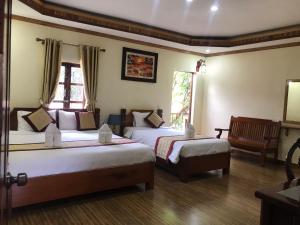 una habitación de hotel con 2 camas y una silla en Xayana Home Villas en Luang Prabang