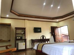 1 dormitorio con 1 cama y TV en la pared en Xayana Home Villas, en Luang Prabang