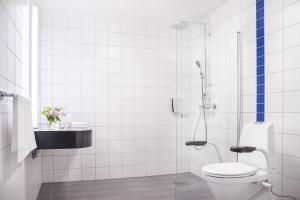 a white tiled bathroom with a toilet and a sink at Milepelen Hotel & Vertshus in Sand