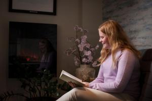 Dziewczyna siedząca na krześle czytająca książkę w obiekcie Milepelen Hotel & Vertshus w mieście Sand
