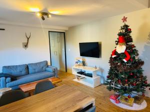 a living room with a christmas tree and a blue couch at Le Chalet - Appartement 5 personnes avec parking in Savignac-les-Ormeaux