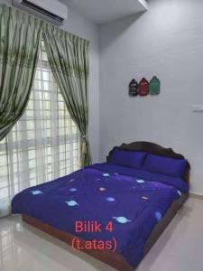 una camera da letto con un letto con lenzuola blu e una finestra di Rafna Homestay a Kota Bharu