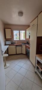 a kitchen with a white tiled floor and a refrigerator at Le Sleipnir - Appartement cantilien calme (proche gare SNCF) in Chantilly