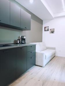 a kitchen with black cabinets and a white couch at Luxury Apartment Teatro in Bolzano