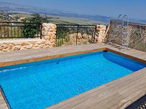 una piscina con terraza de madera en צימר בקתה מול הנוף, en Safed