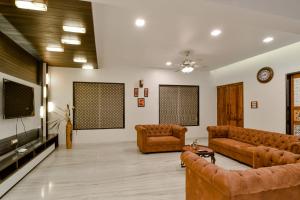 a living room with couches and a flat screen tv at Villan Villa Luxurious Mountain View Biggest Pool in Lonavala